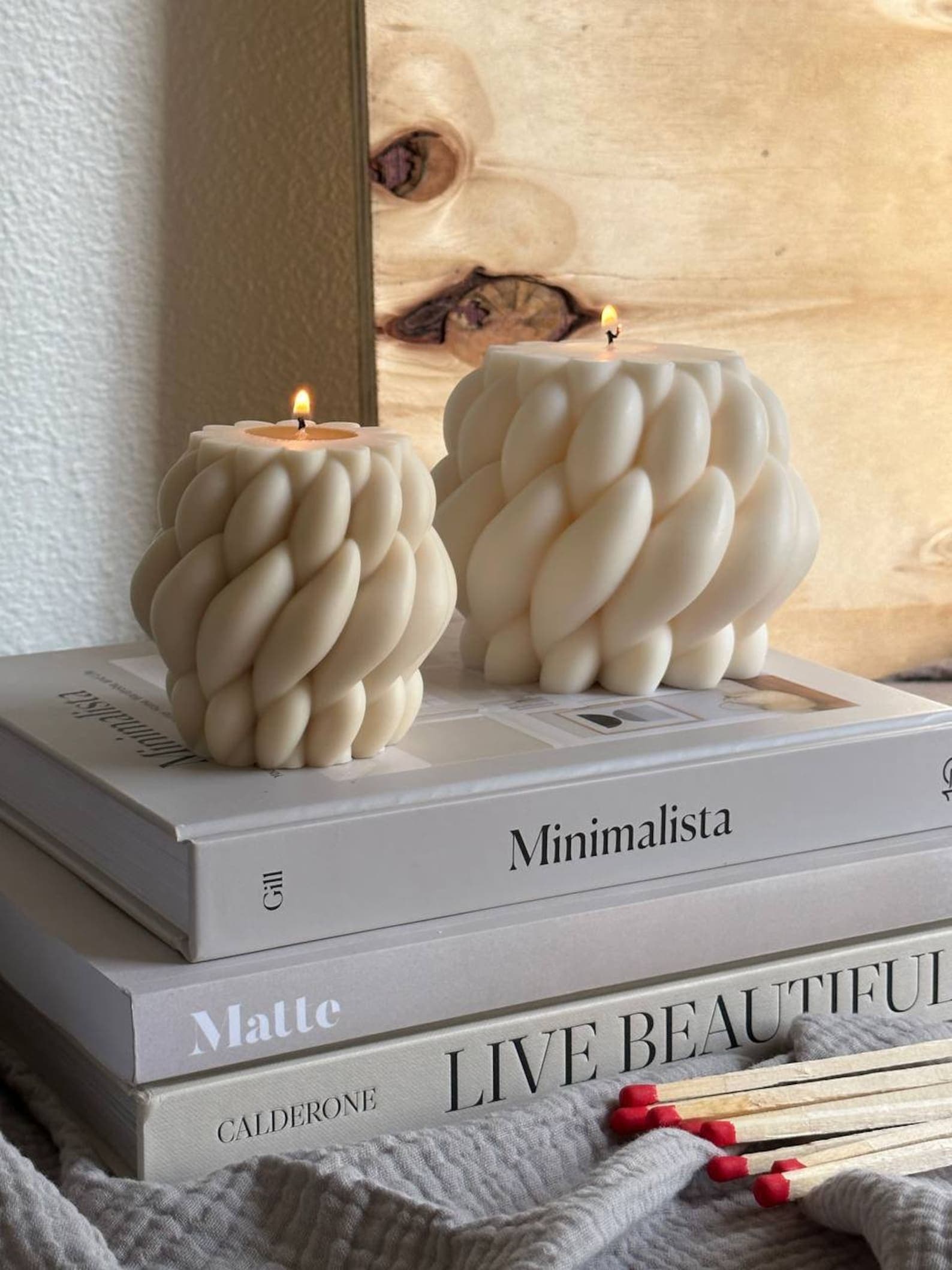A duffle bag, dopp kit and ceramic mug sit atop a wood table in front of a wall of art prints.